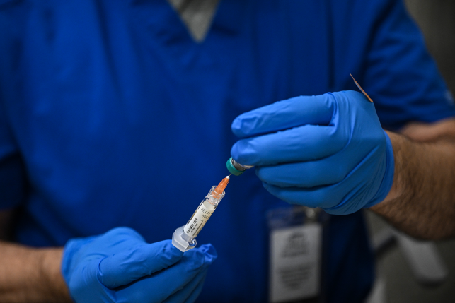 Gloved hands hold syringe