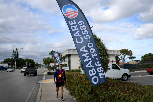 Person walks in front of Obamcare sign