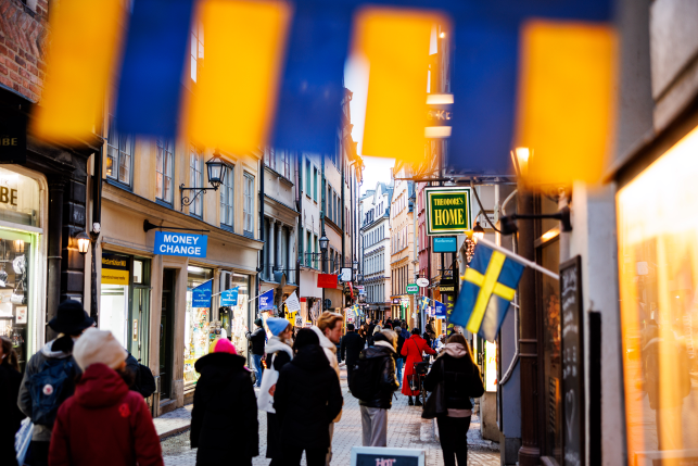 Swedish flag flies over busy street with pedestrians