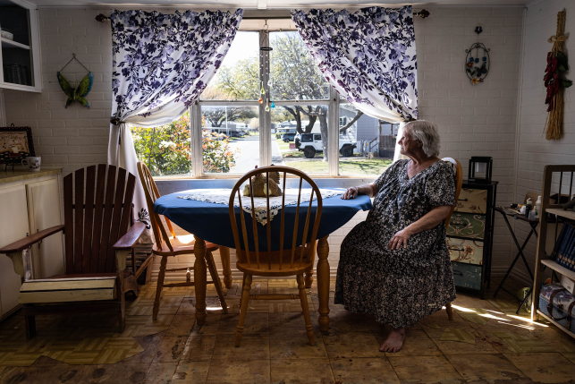Woman sits at kitchen table looking out the window
