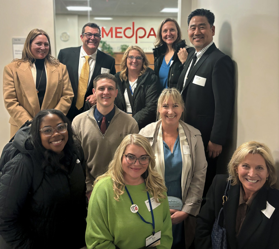 Group of people smiling and posing in front of the door of Medpac
