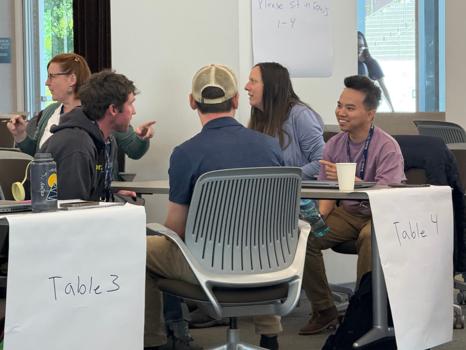 Group of students sitting around a table labeled 'Table 4' having a discussion