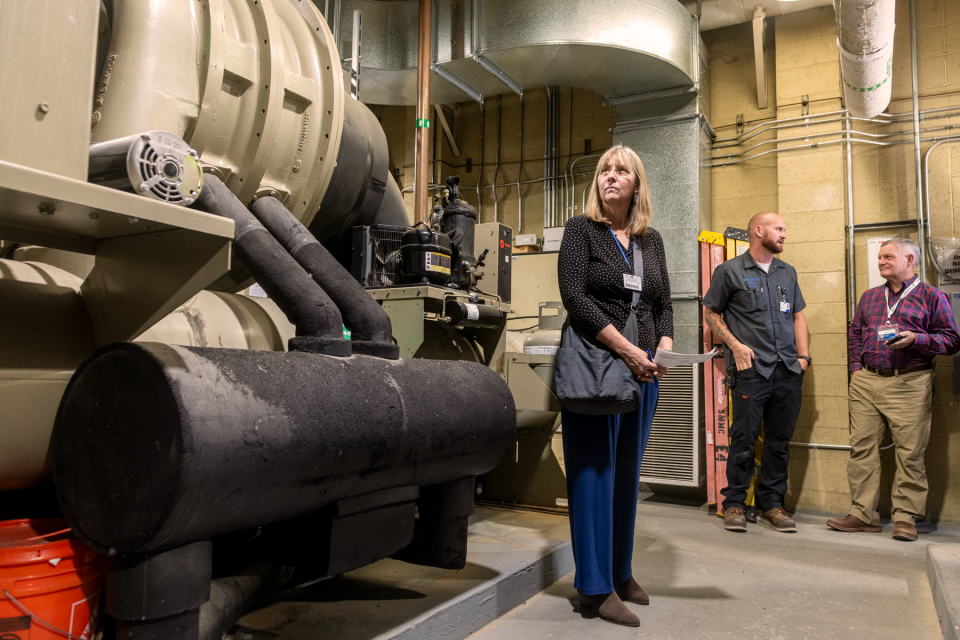 Woman standing next to power plant machinery while inspecting the area