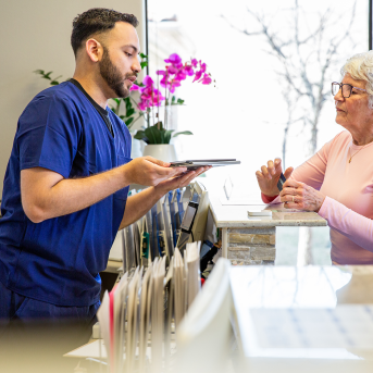 Medical professional in scrubs hands paperwork to patient
