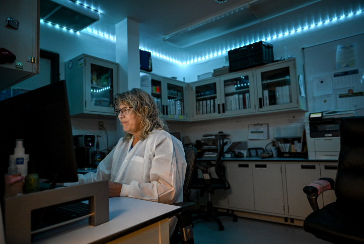 Tech in front of computer in white lab coat.