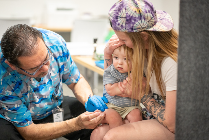 Mom holds baby who is receiving vaccination injection.