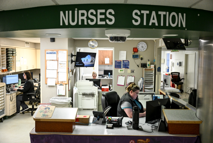 Nurses working at computers in a cluttered hospital nurses station 