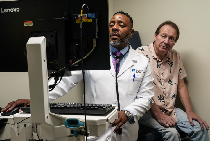 Doctor looks at computer scren in front of patient