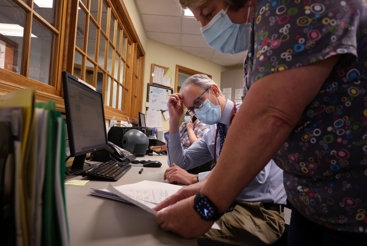Two medical professionals look at paperwork on desk