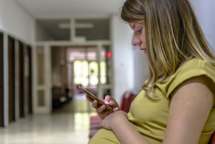 Low-income patient with cell phone in hospital waiting room