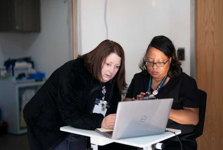 two clinic workers look at laptop