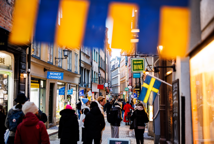 Swedish flag flies over busy street with pedestrians