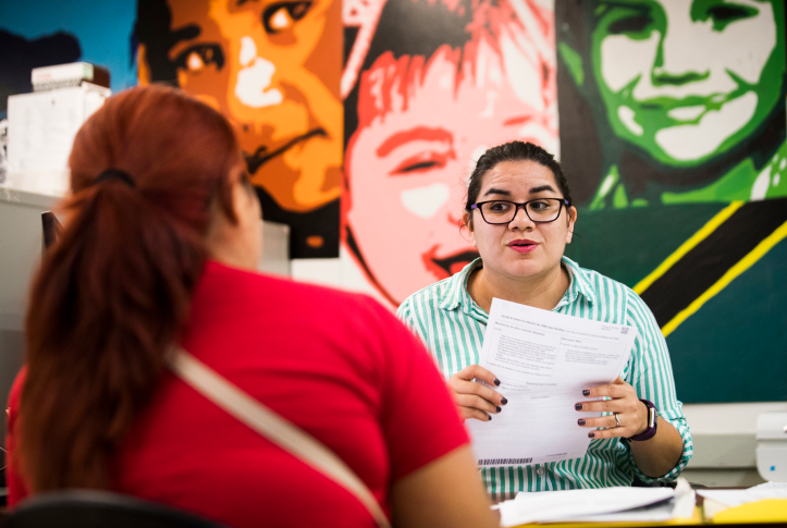woman at desk with paperwork helps another women
