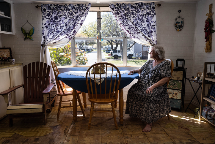 Woman sits at kitchen table looking out the window