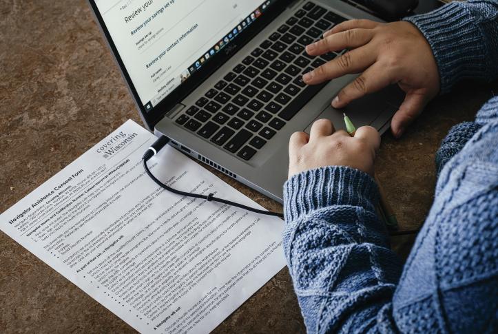 Man with paperwork works at his laptop