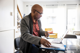 Man sits with papers next to laptop