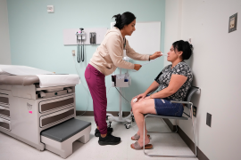 Medical assistant takes oral temperature of seated patient