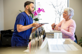 Medical professional in scrubs hands paperwork to patient